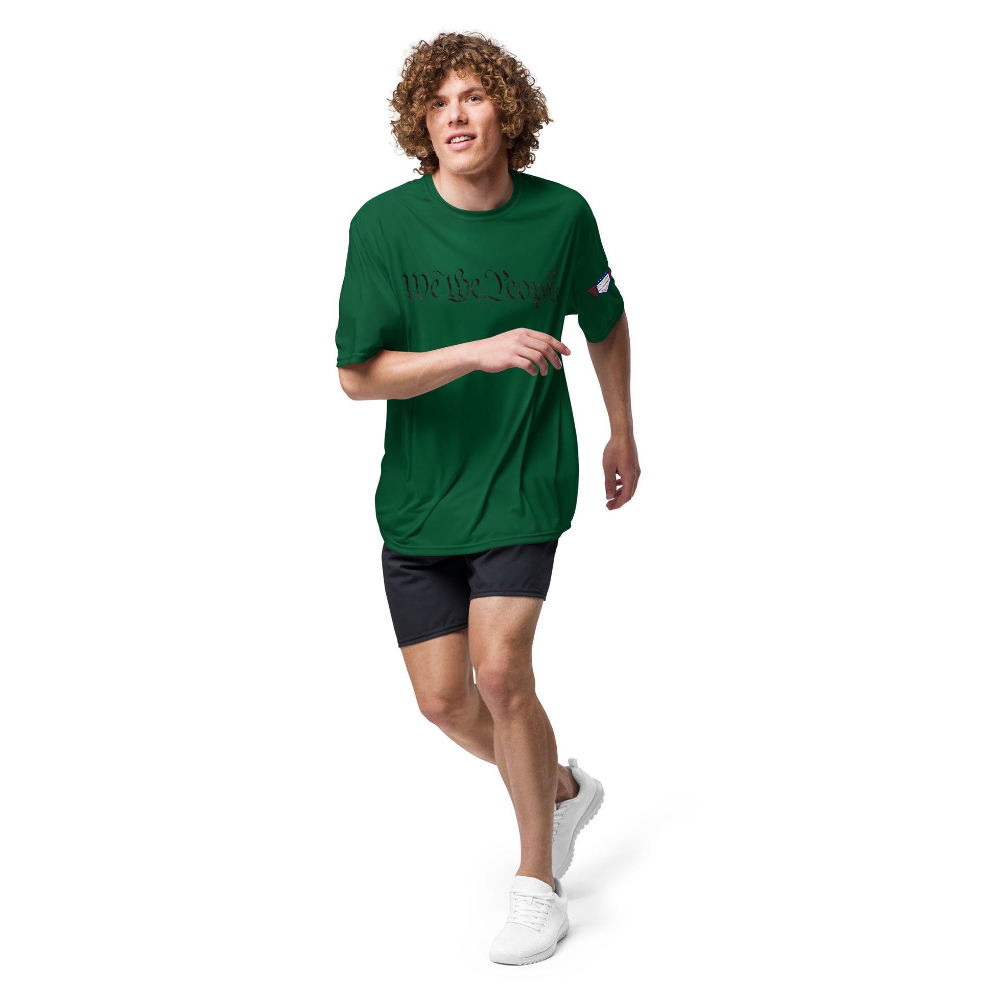 Curly-haired dude dashing in forest green "We The People" tee, flag patch, gym shorts