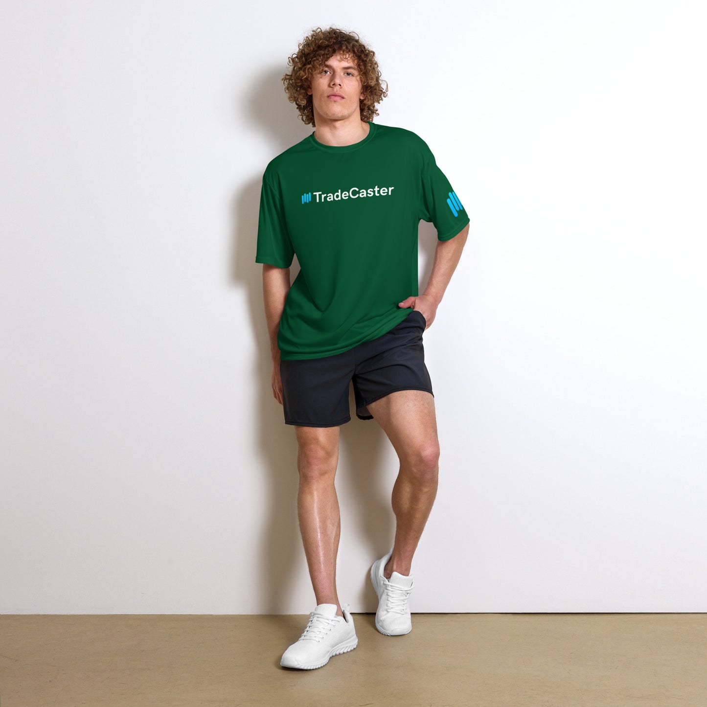 Curly-haired model flexes in forest green TradeCaster tee, cyan logo popping on chest