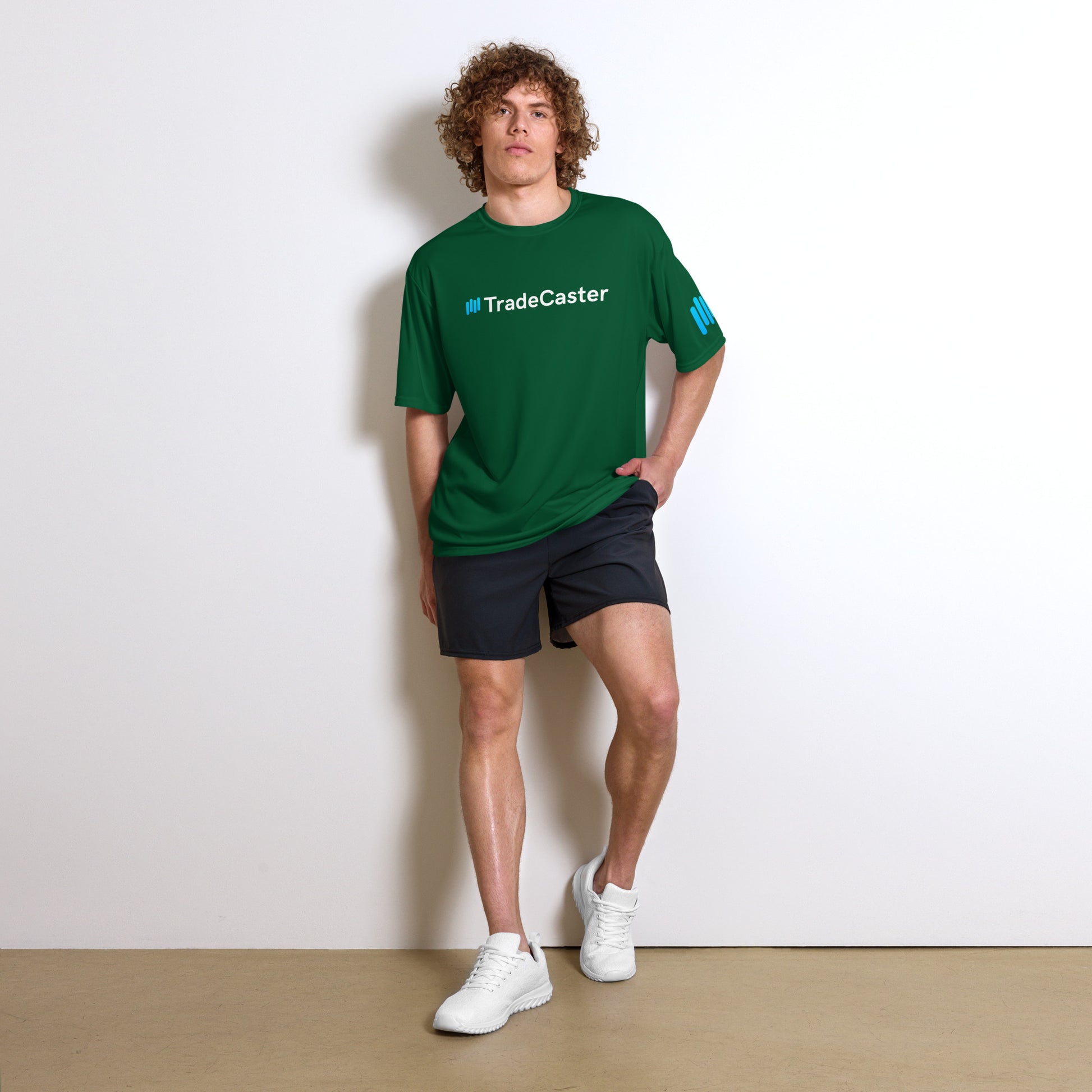 Curly-haired model flexes in forest green TradeCaster tee, cyan logo popping on chest