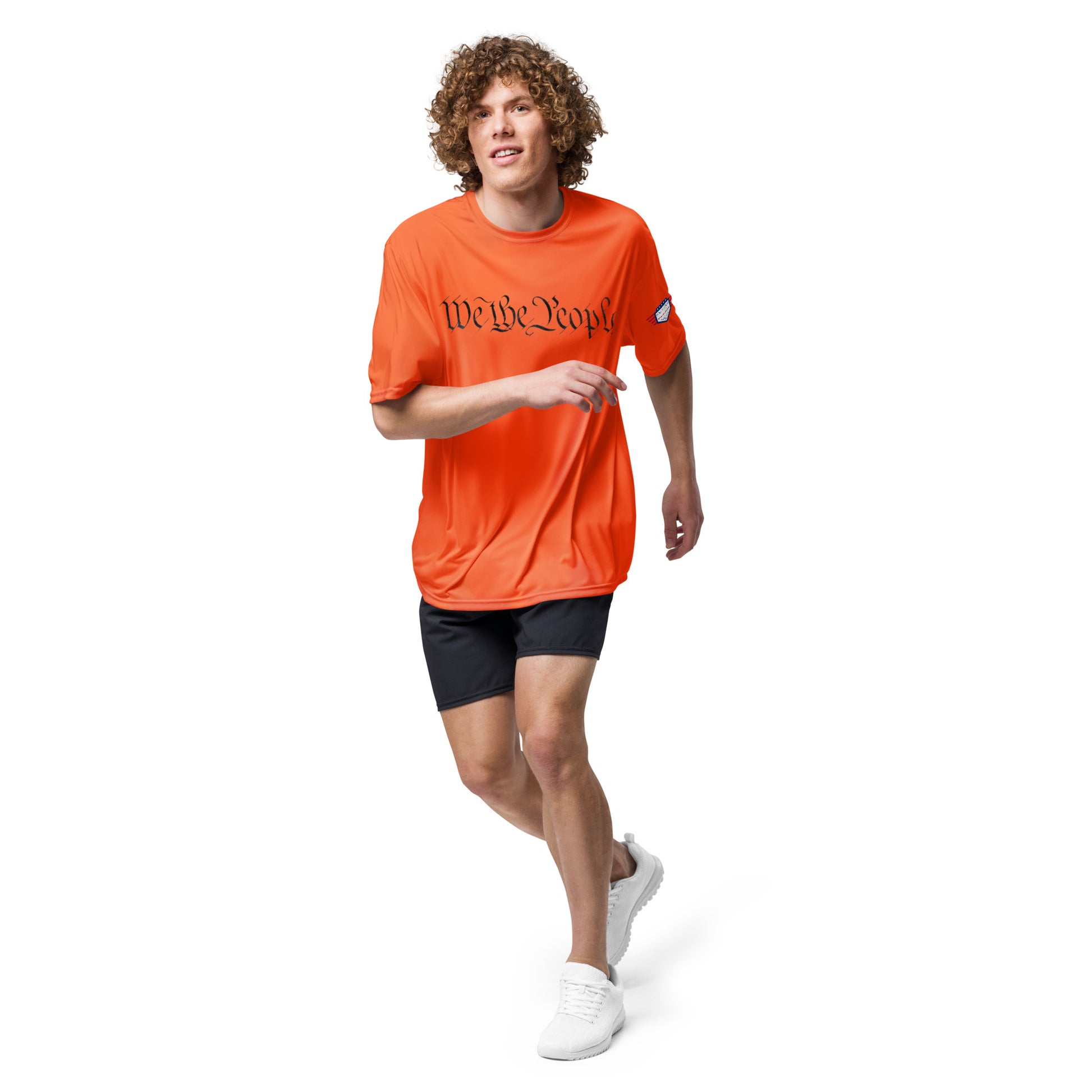 Curly-haired man jogging in orange "We The People" performance tee, sweat-ready