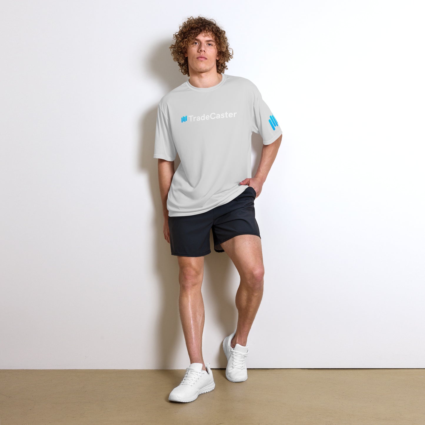 Curly model striking front pose in gray TradeCaster performance tee, cyan #TradeCaster print front and center