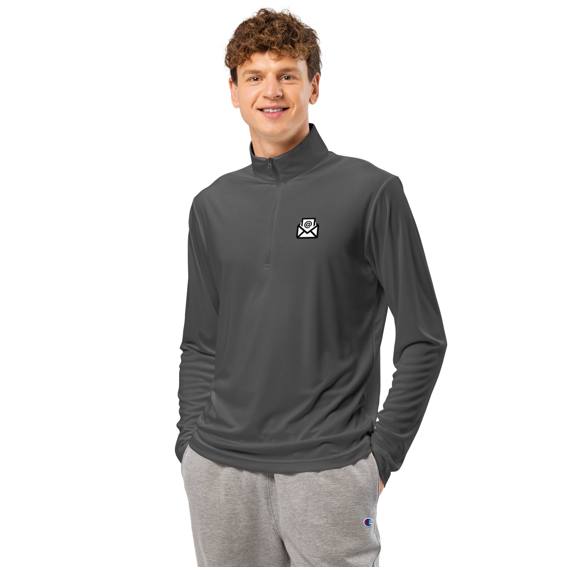 Man grinning in grey quarter-zip pullover showing white envelope logo on left chest
