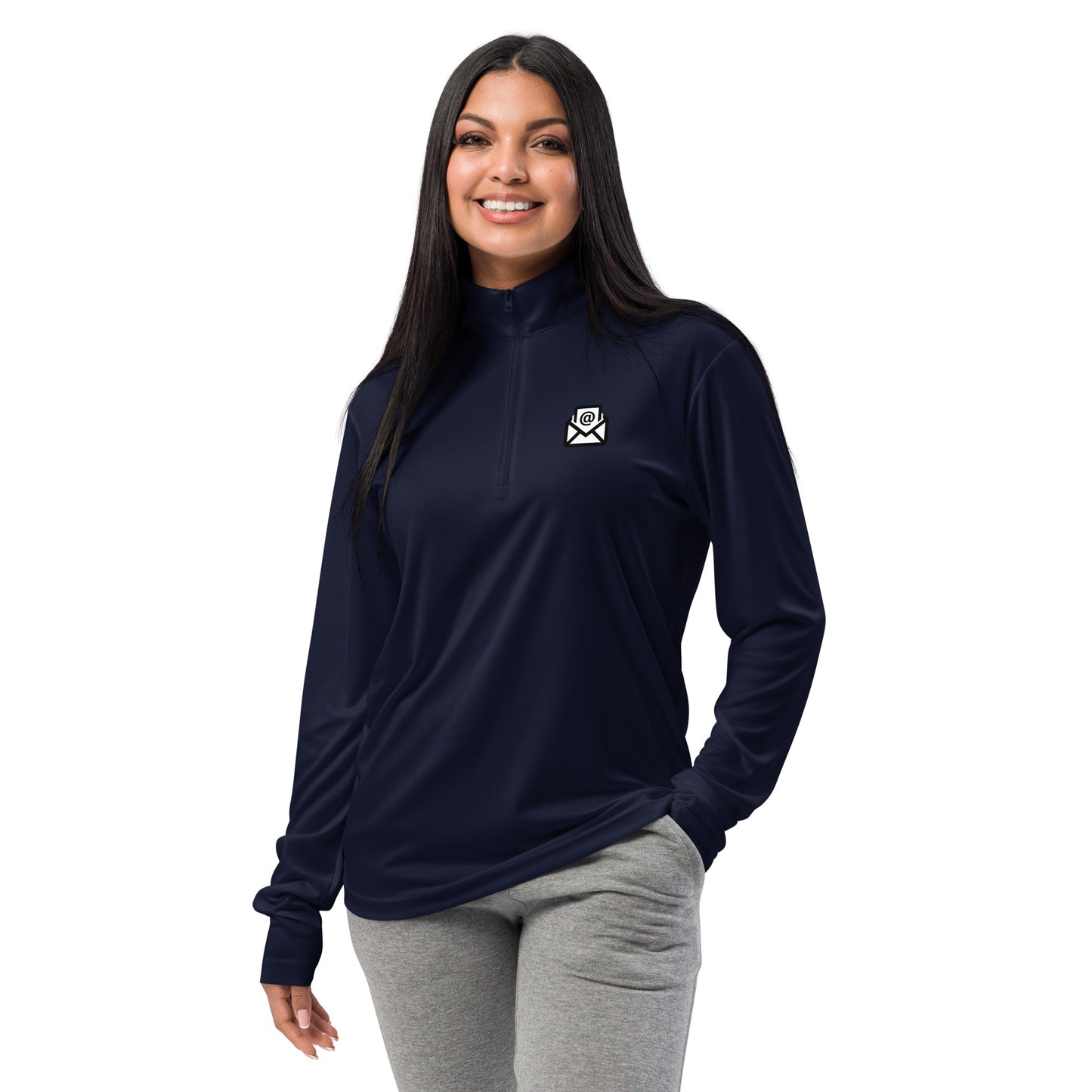 Smiling woman modeling black quarter-zip pullover with white email envelope icon on chest, hands-in-pockets pose
