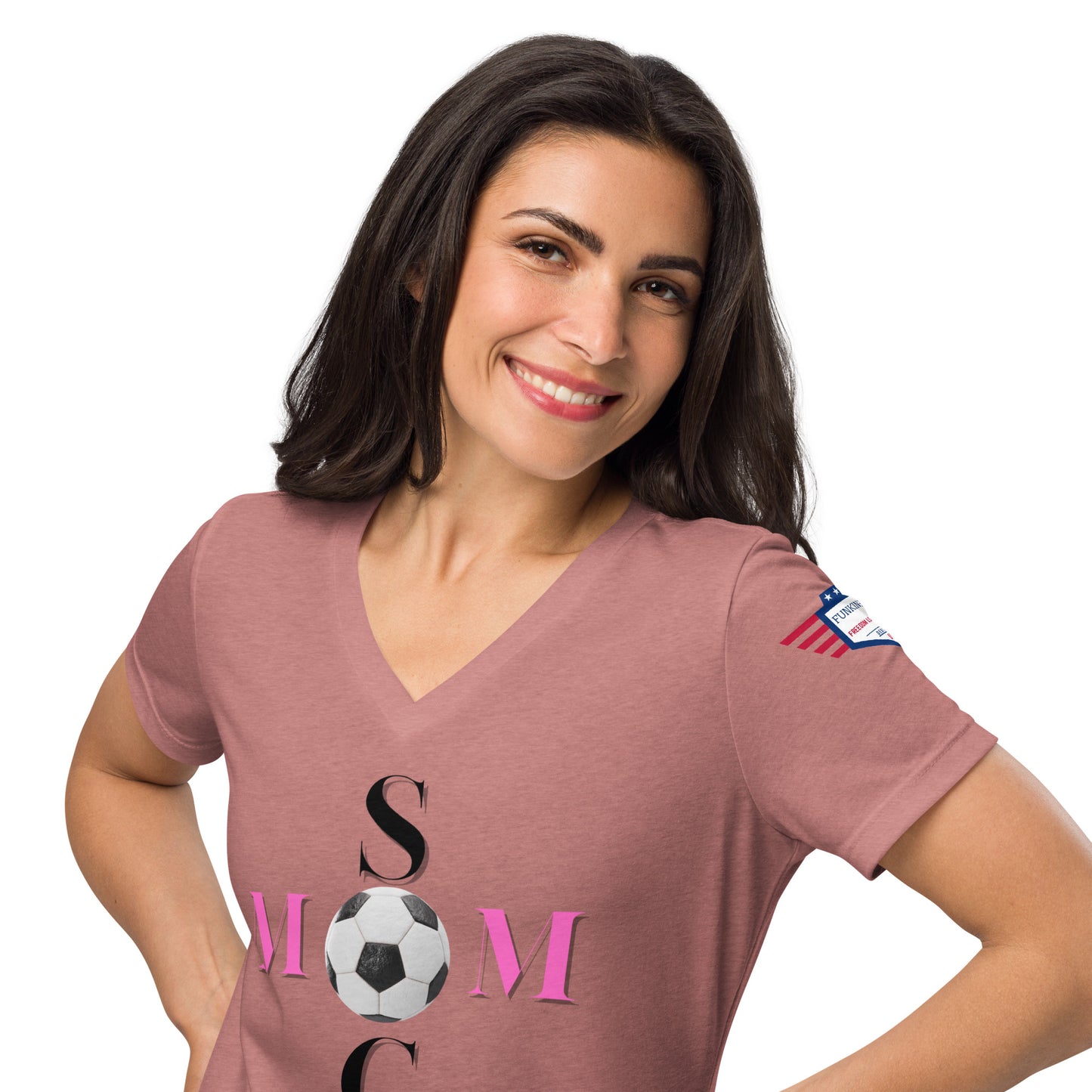 Model smiling in mauve v-neck Soccer Mom tee with pink MOM print, black soccer ball, flag patch on sleeve
