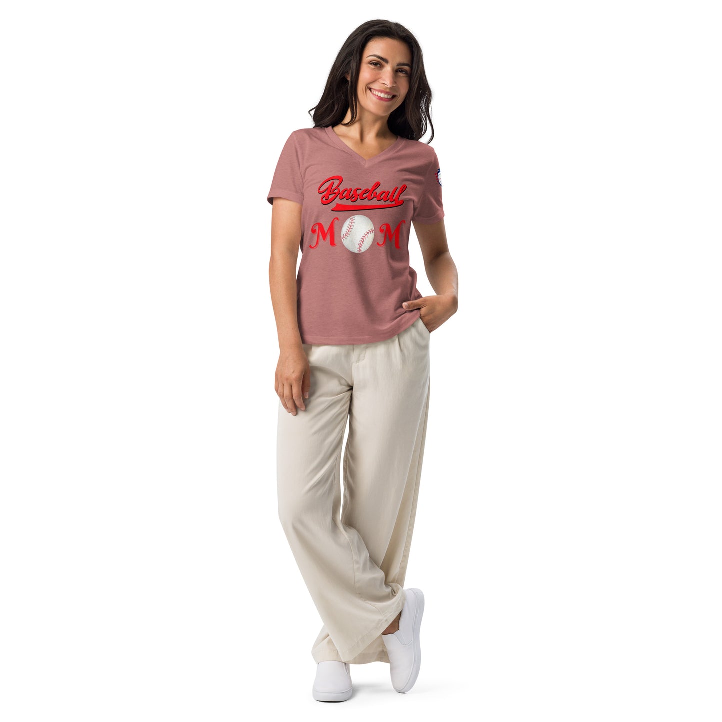 Model smiling in heather mauve v-neck Baseball Mom tee, red cursive "Baseball Mom" print with baseball, hands in beige pants pockets