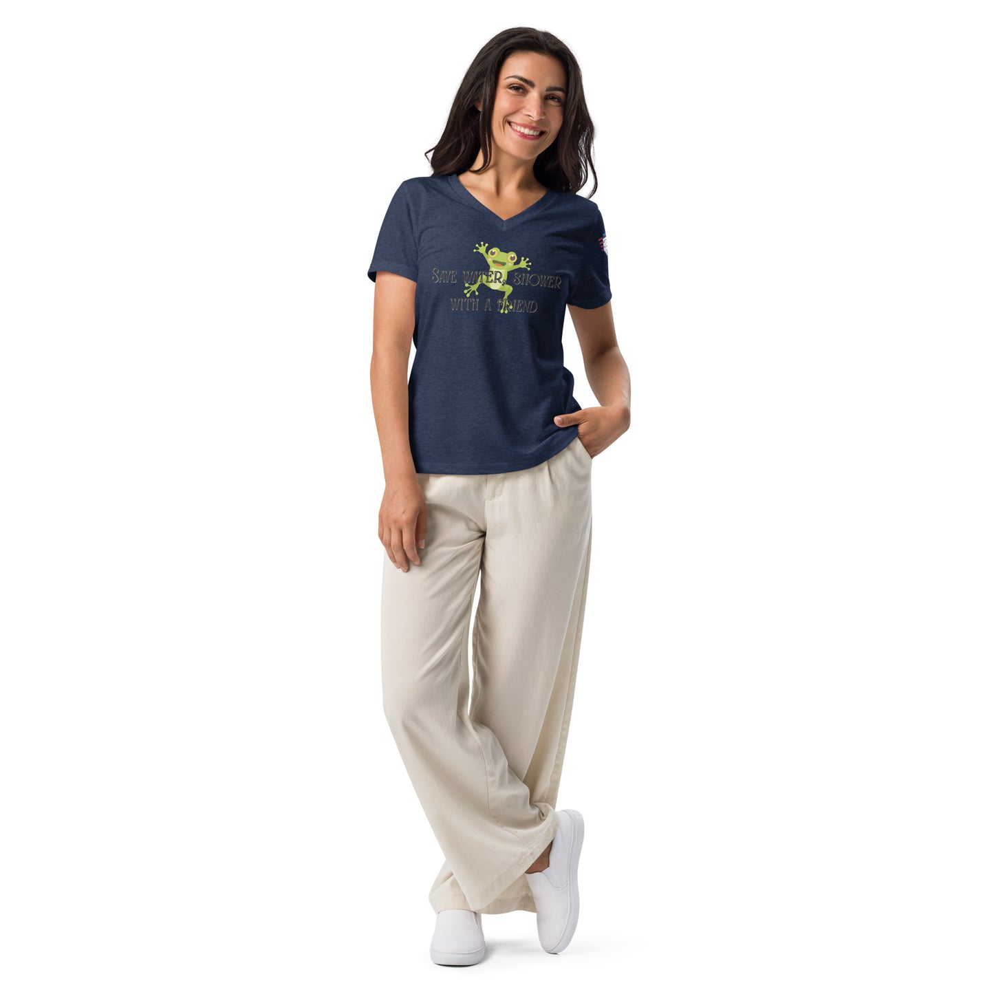 Woman in heather navy v-neck tee, hands in pockets over beige pants and white sneakers, partial text visible
