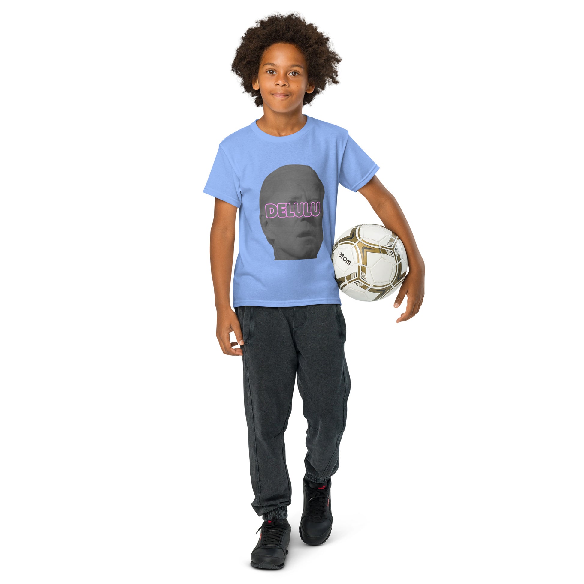 Front view of kid holding soccer ball in Carolina blue Delulu youth t-shirt, full gray face pink "DELU" design