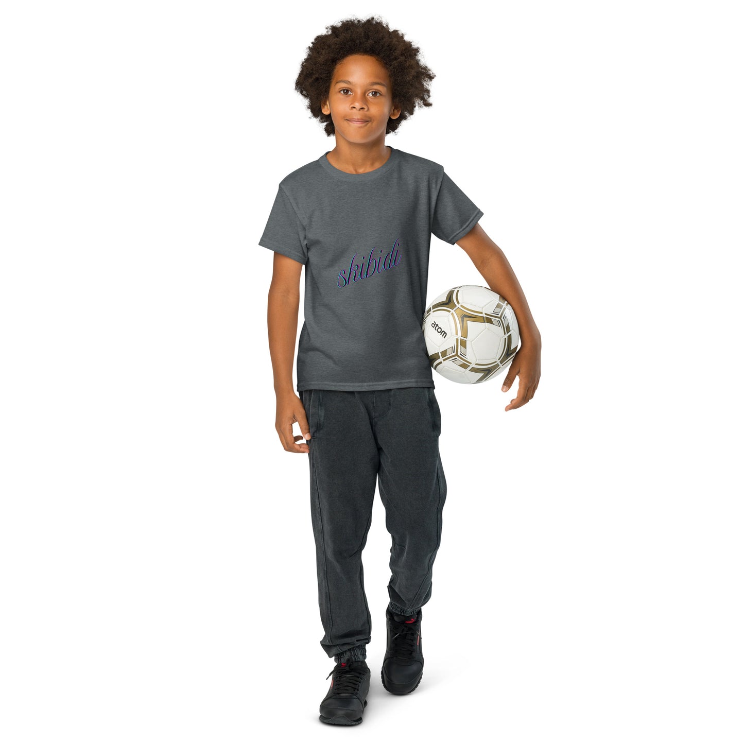Young model holding soccer ball in dark heather gray "skibidi" youth tee, purple script front
