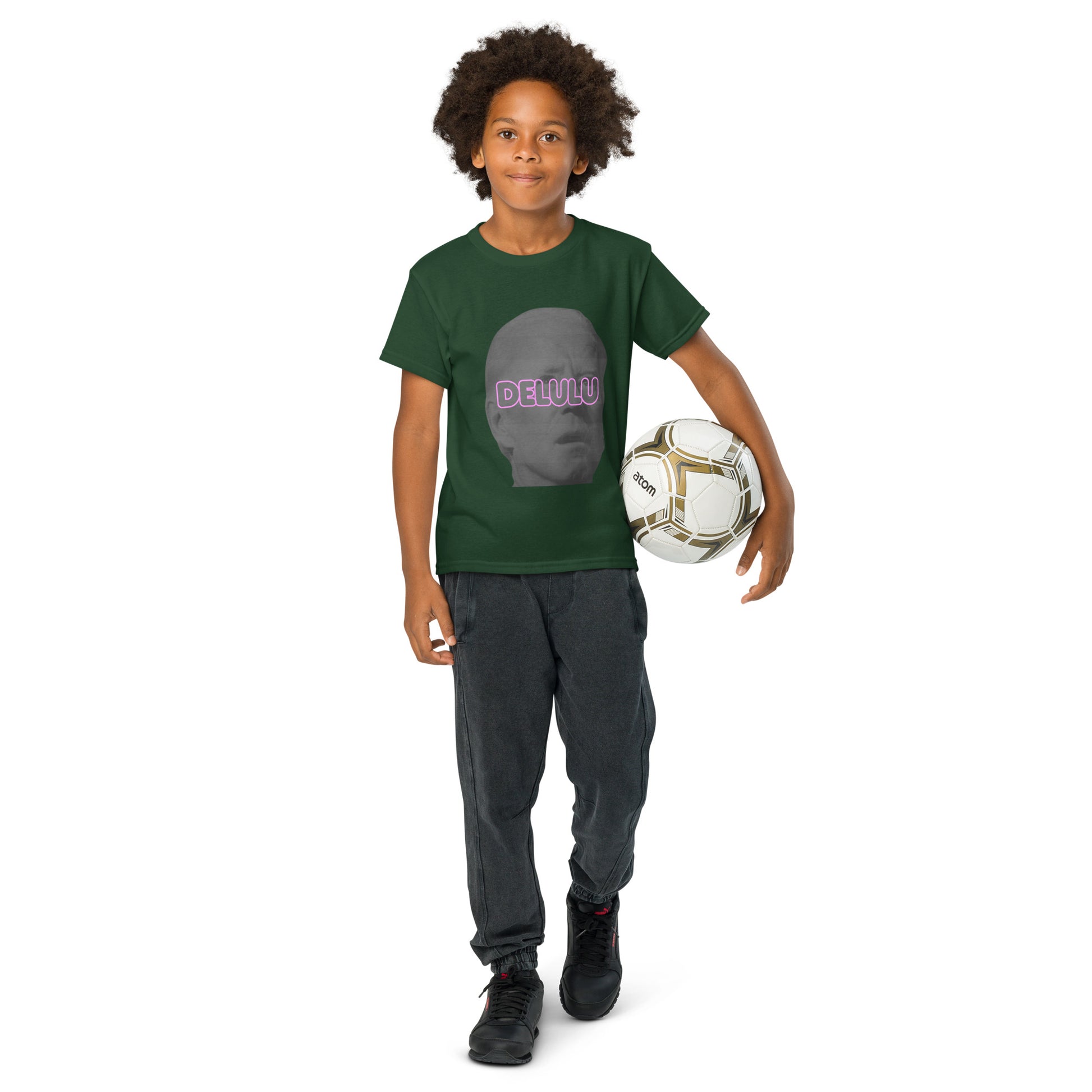 Boy holding soccer ball in forest green Delulu youth tee, pink "DELULU" on gray face popping
