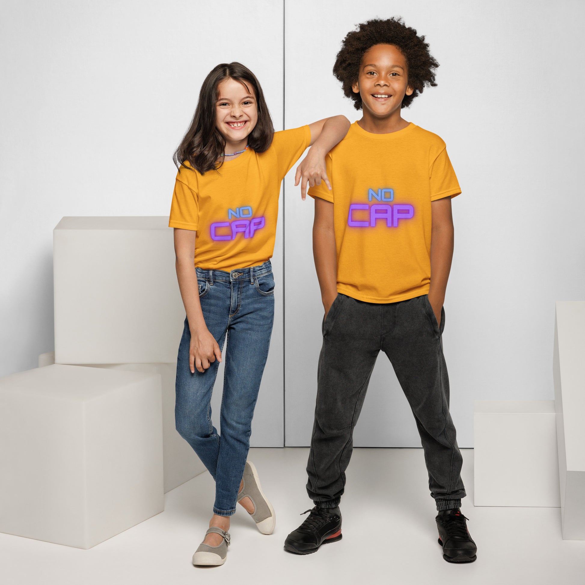 Youth girl and boy models grinning in gold "NO CAP" neon blue-purple print t-shirts, front view against white blocks