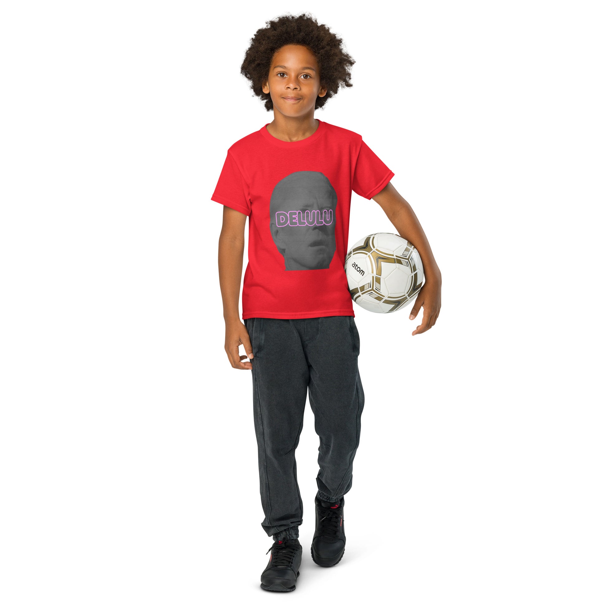 Kid with soccer ball owns red Delulu youth t-shirt, pink "DELULU" text on gray face graphic